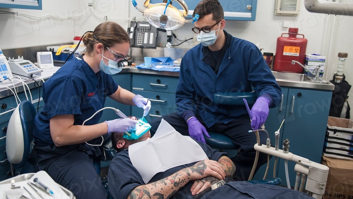 Dos dentistas atendiendo a un paciente en el consultorio