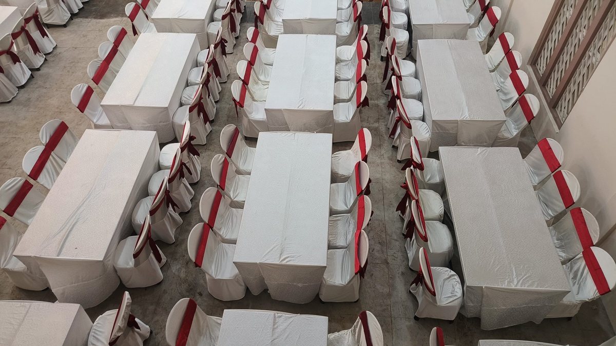 Salón montado con mesas largas y sillas vestidas