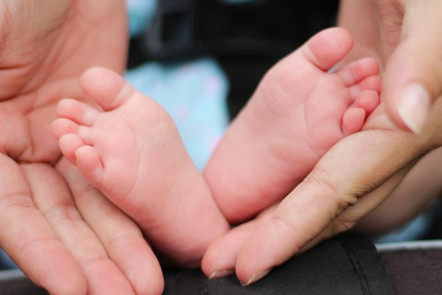 Pies de un bebé en las manos de su mamá